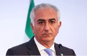 அறிக்கை வெளியிடும் ஈரானிய பட்டத்து இளவரசர் ரெசா பஹ்லவி மற்றும் பின்னணியில் ஈரான் தேசியக் கொடி.