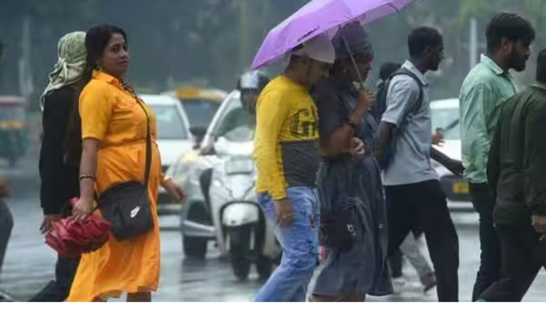 சென்னையில் மழை பெய்யும் நிலையில் குடையுடன் செல்லும் மக்கள் மற்றும் கருமேகங்களுடன் காணப்படும் வானம்